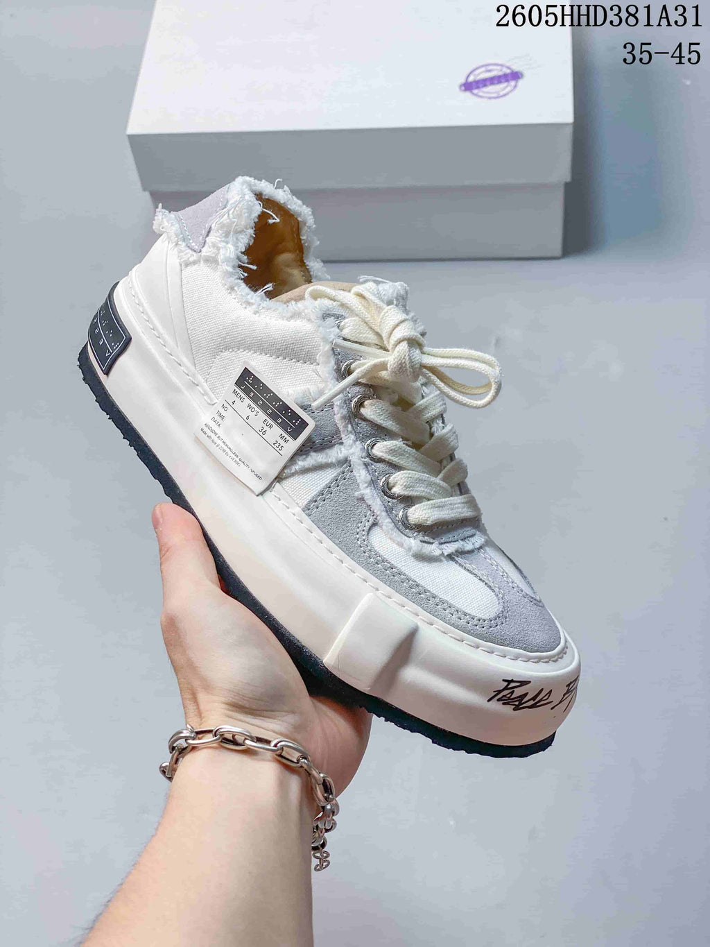 Angled side view of a white and gray xVESSEL sneaker with a visible size label