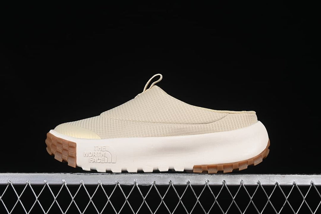 Side profile of a light neutral mule sneaker with a white midsole and brown outsole.