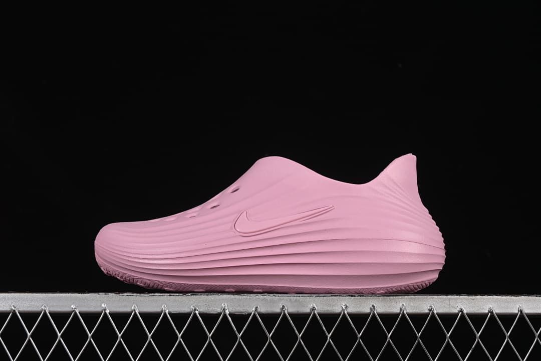 Side view of a pink Nike ReactX Rejuven8 slip-on shoe against a black background.