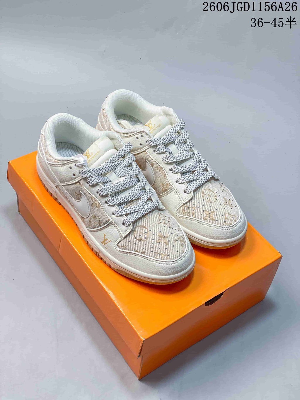 Pair of cream and white low-top sneakers with tan patterned panels and coordinating laces