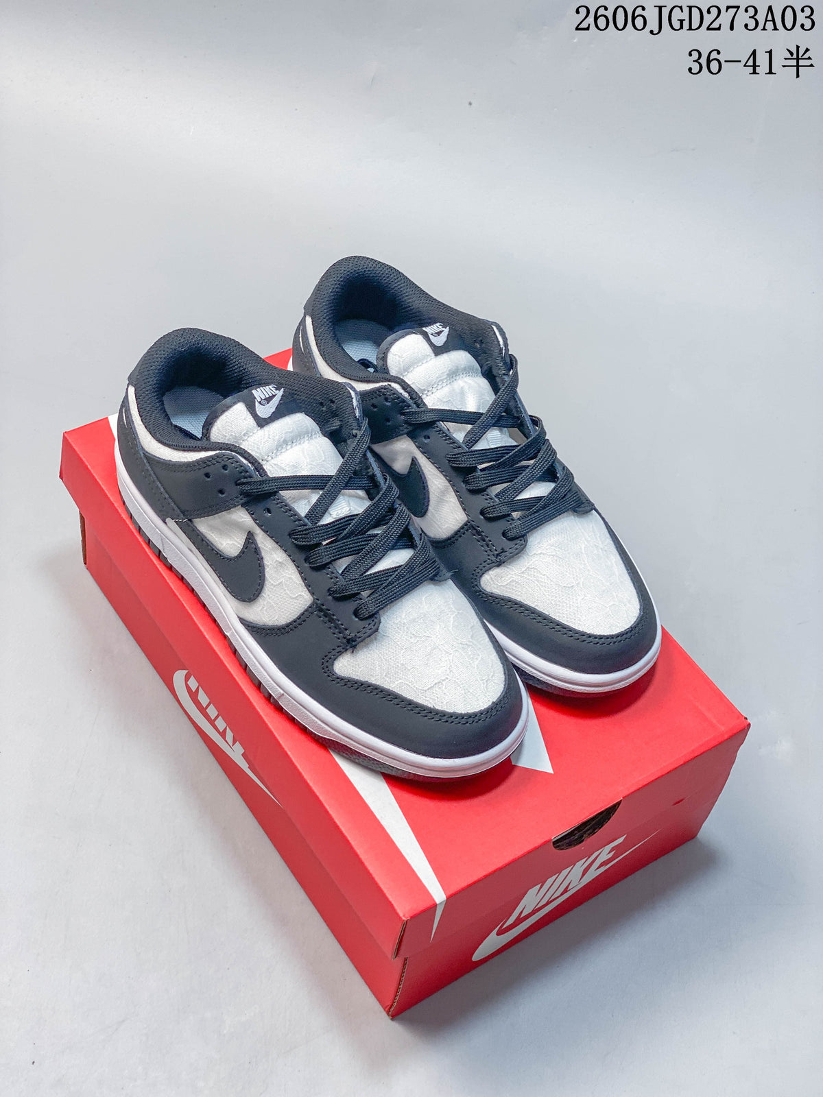 Black-and-white low-top Nike Dunk sneakers with patterned panels on a red shoebox