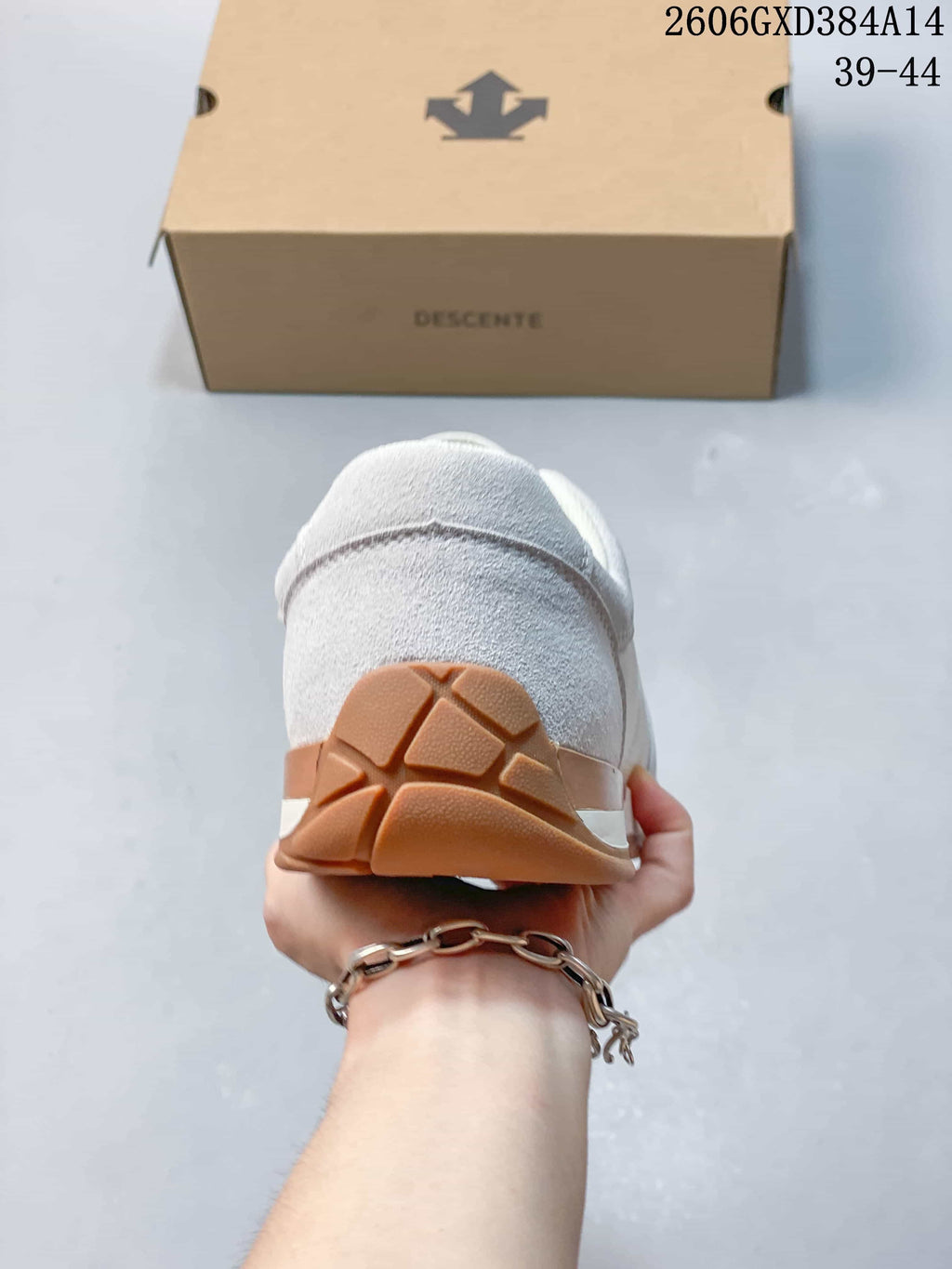 Rear view of a white and light gray sneaker with a gum-colored heel outsole.