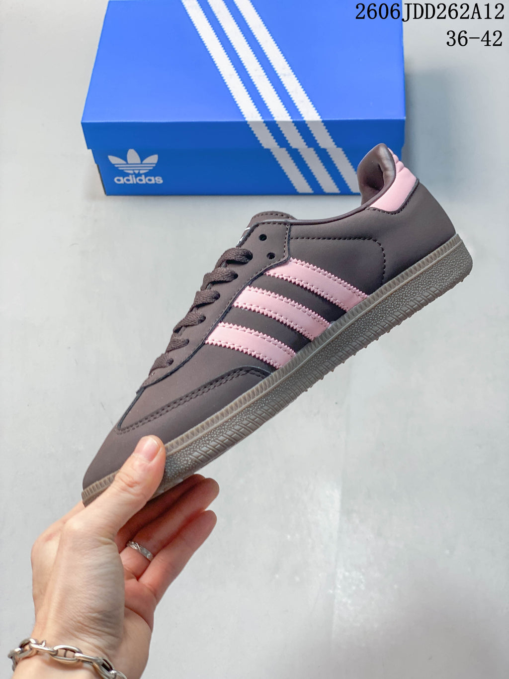 Side profile of a dark grey low-top sneaker with pink stripes and a textured grey outsole.