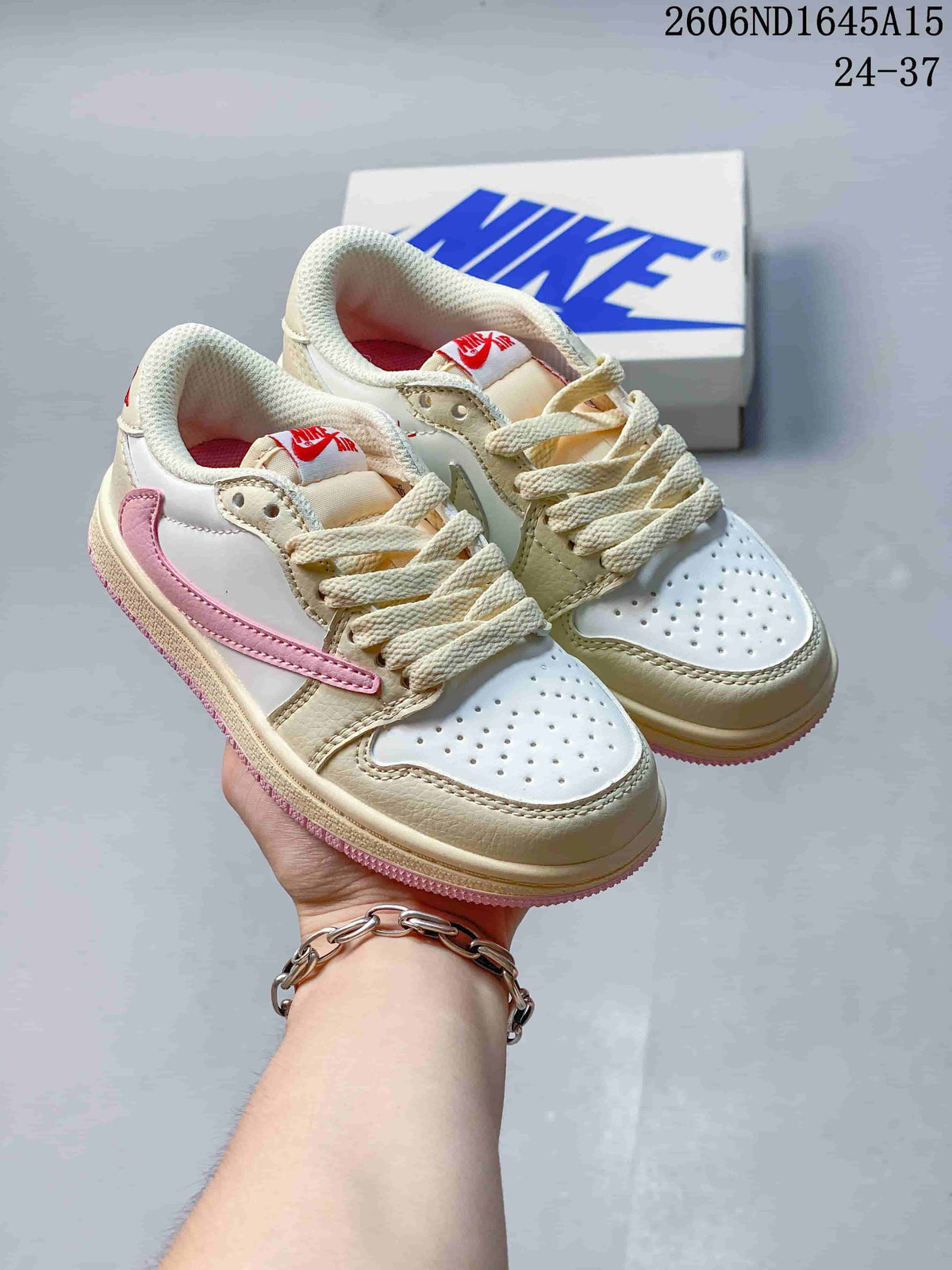 Pair of white and beige kids’ low-top sneakers with pink side details and pink outsoles.