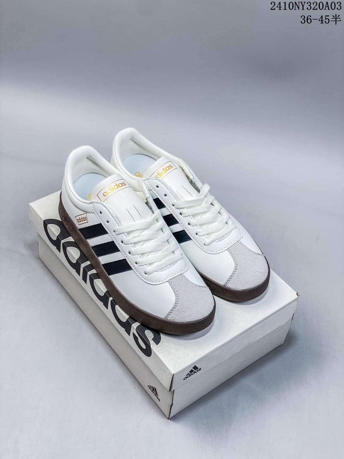 Pair of white Adidas VL Court 2.0 sneakers with navy stripes, gray toe panels, and brown soles
