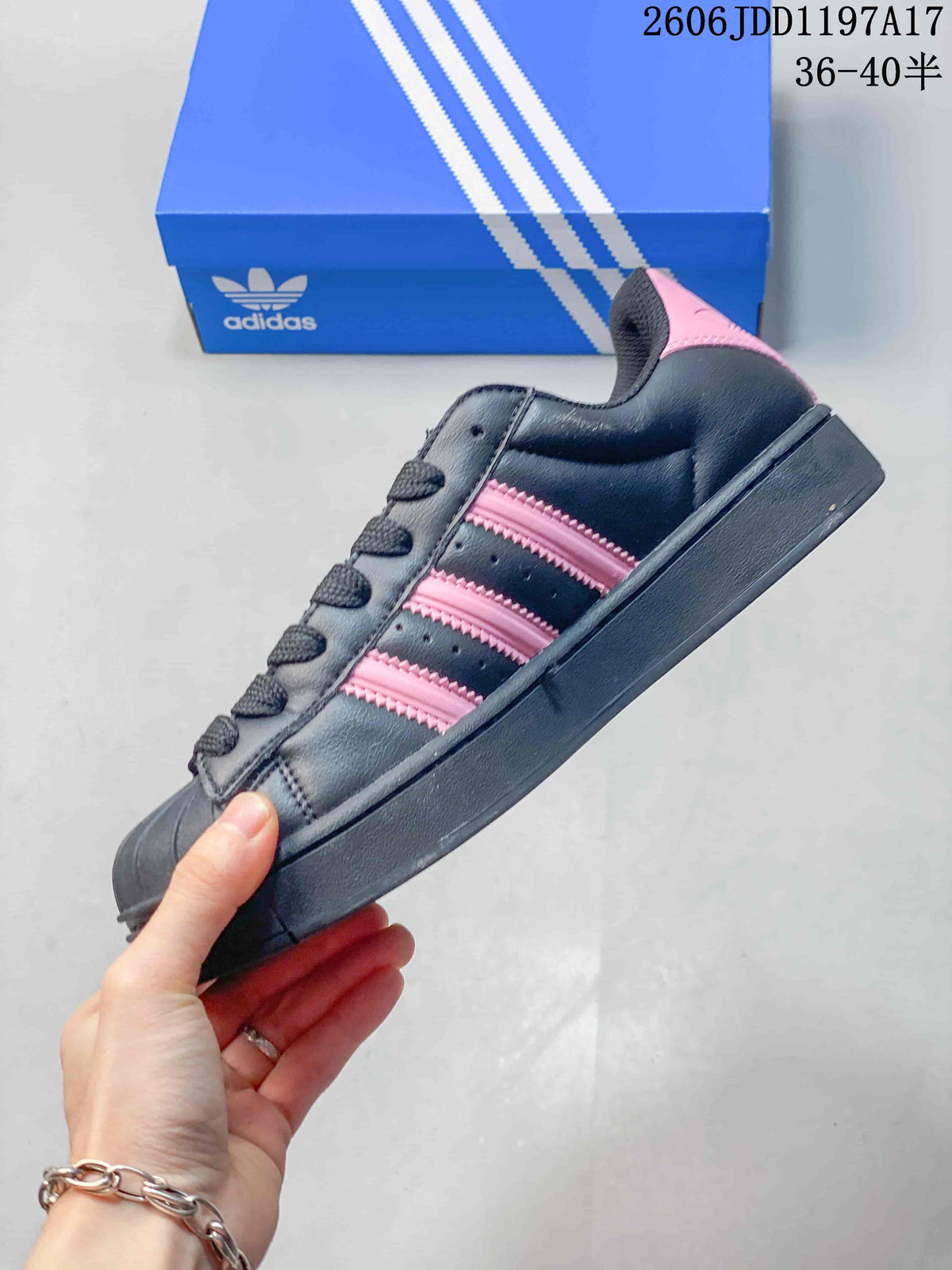 Side view of a dark lace-up sneaker with pink stripes and a shell toe.