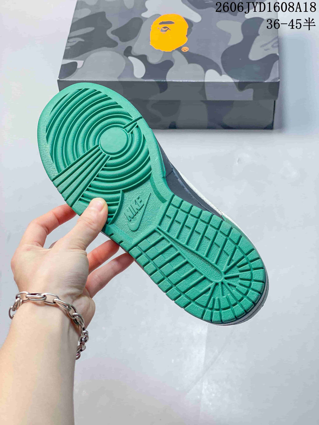 Green outsole of the sneaker beside a camouflage-patterned box