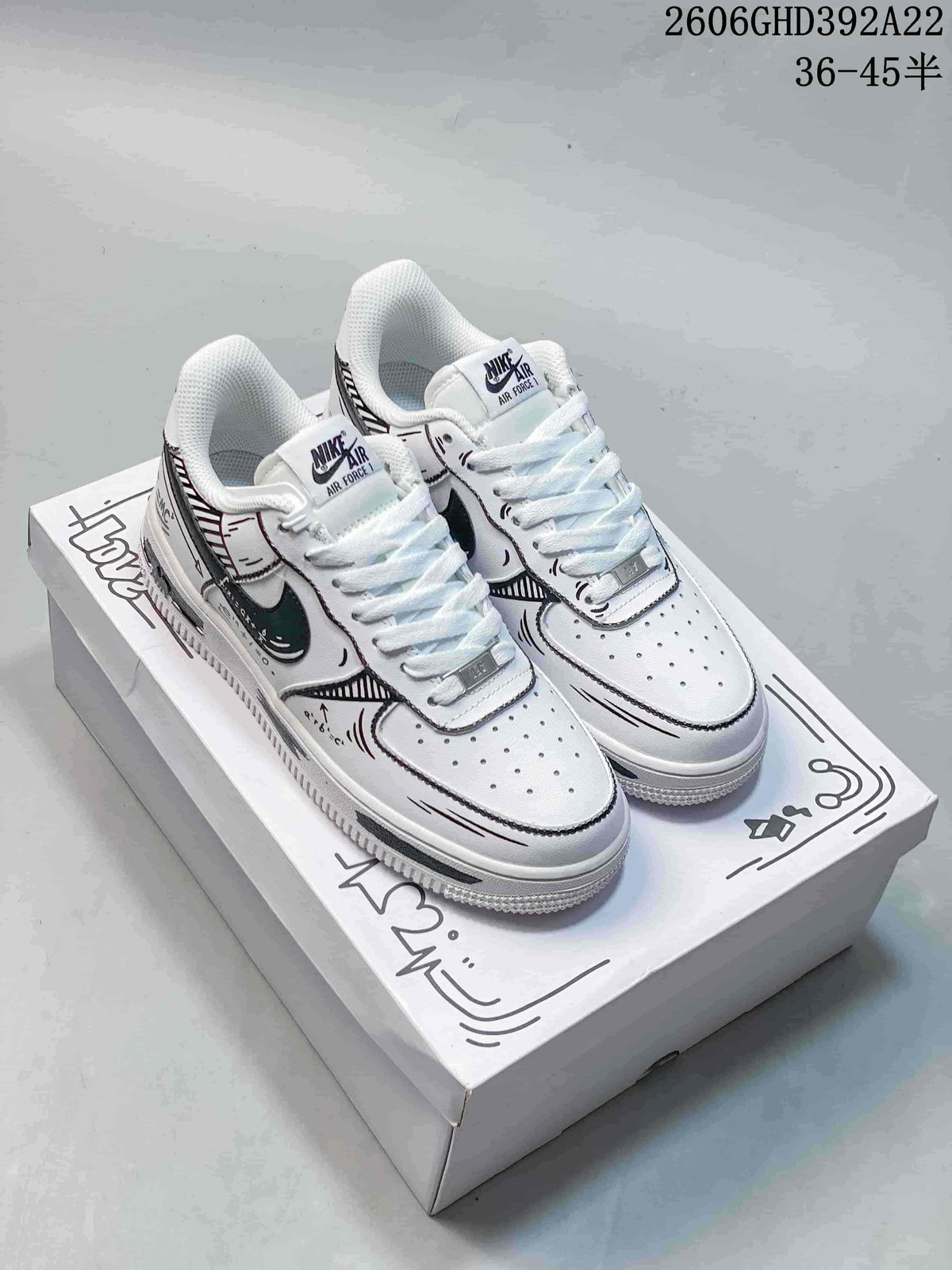 Pair of white Nike Air Force 1 ’07 Low sneakers with black graphic detailing, shown on a decorated shoe box.