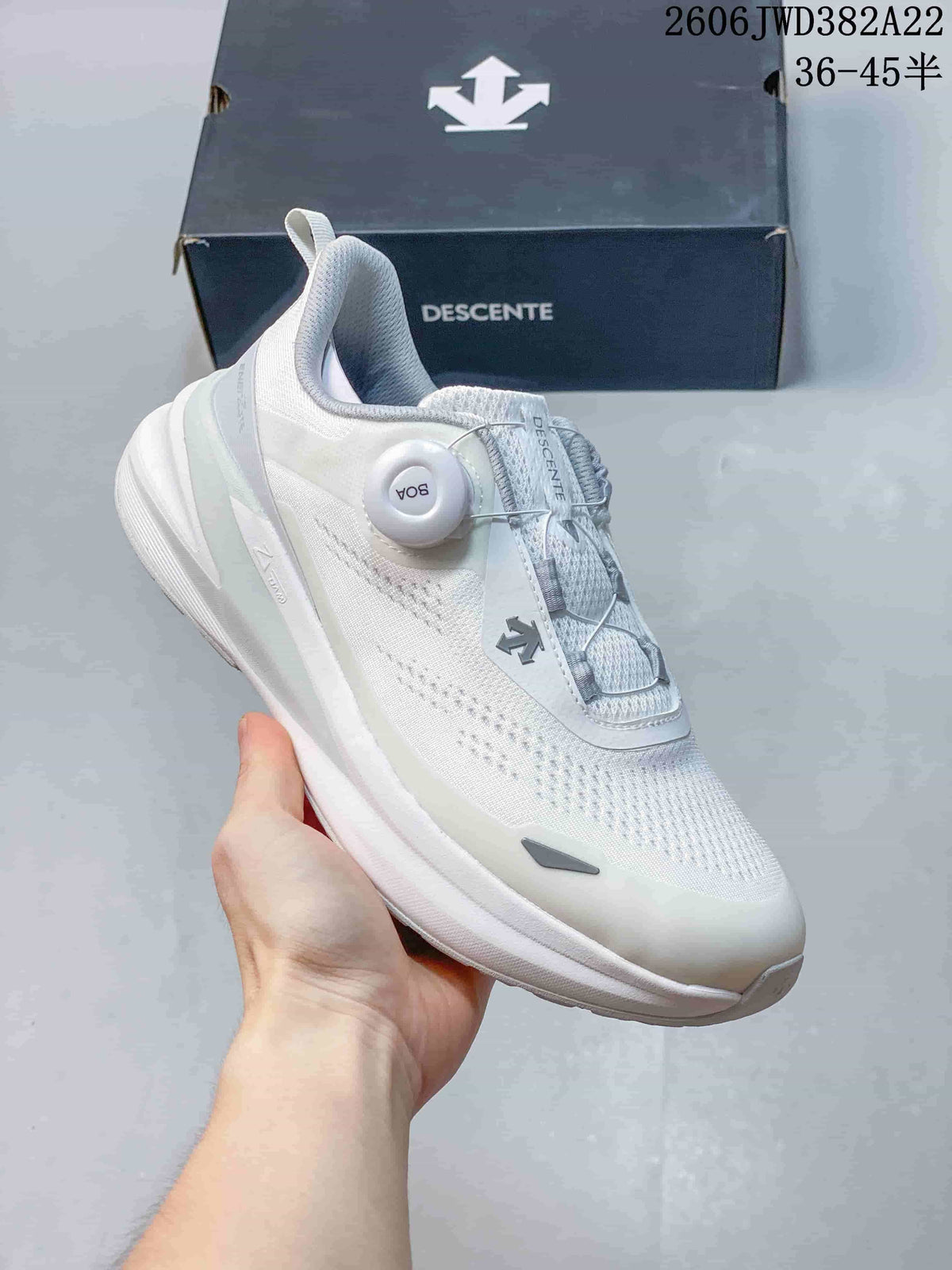 Angled side view of the white DESCENTE running shoe with knit upper and BOA dial.