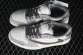 Pair of white and grey low-top sneakers viewed from above, showing perforated toe boxes, dark laces, and contrasting side panels.