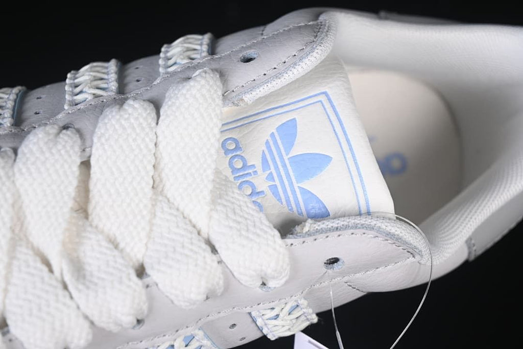 Angled close-up of the white laces, tongue branding and upper.