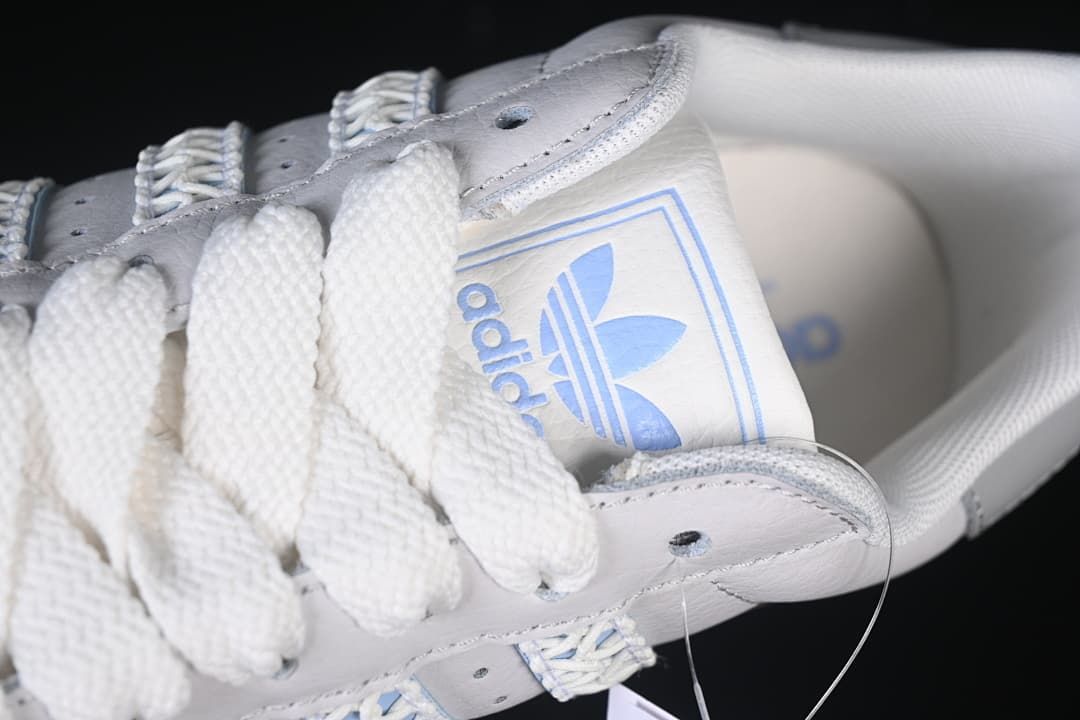 Angled close-up of the white laces, tongue branding and upper.