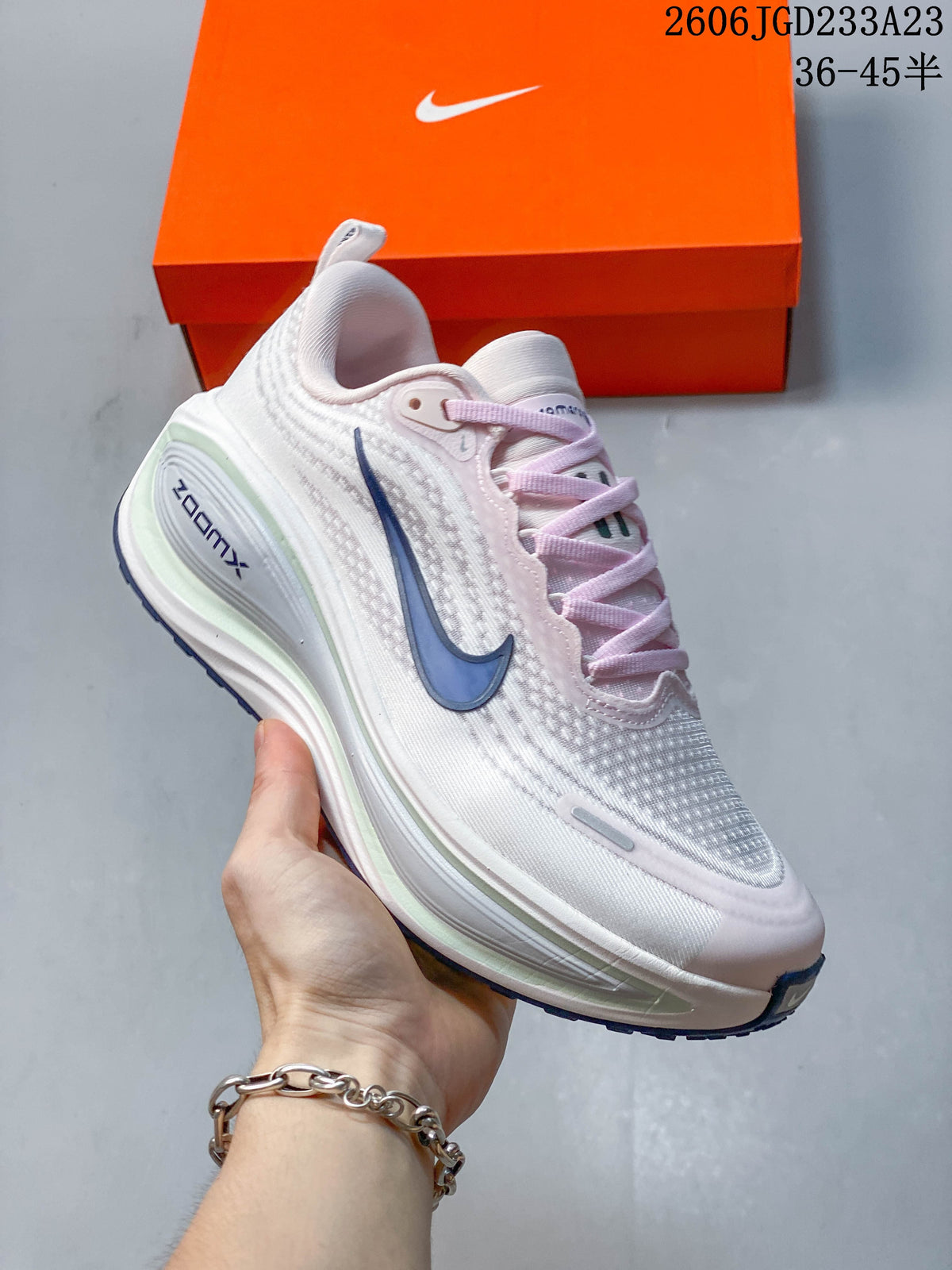 Close side view of the white Nike Vomero Plus with blue Swoosh detail and layered-looking midsole.