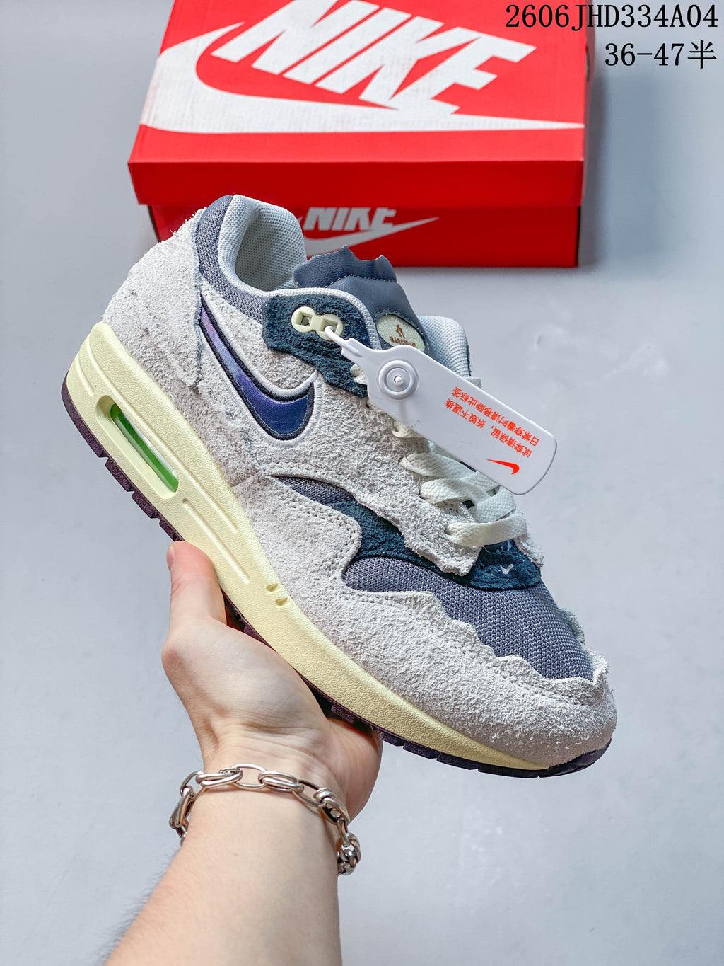 Nike Air Max 1 sneaker in gray, white, and pale blue with a light-colored midsole.