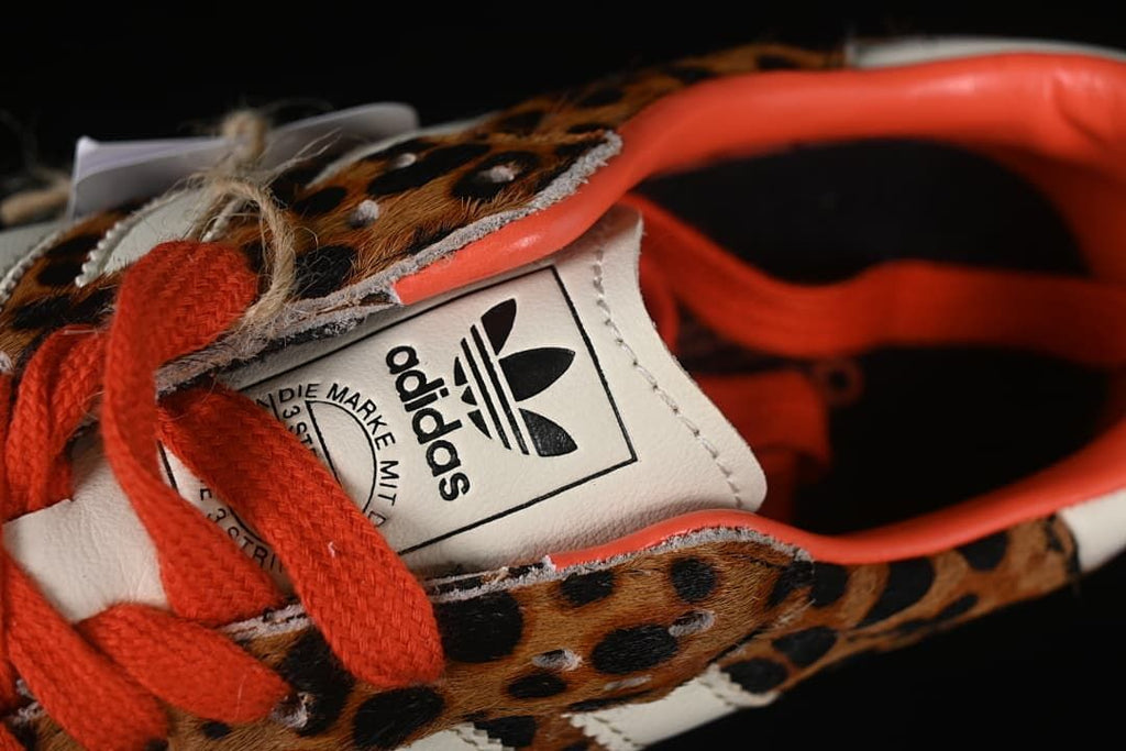 Close-up of the Adidas tongue label and orange-red laces