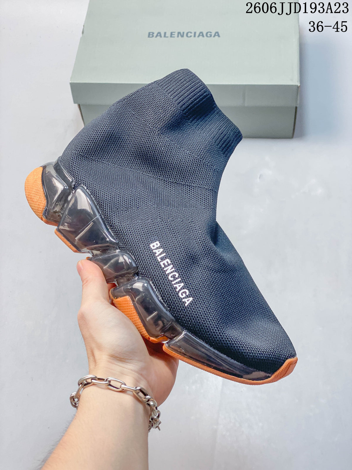 A navy Balenciaga sock-style sneaker with orange sole accents, shown from the side.