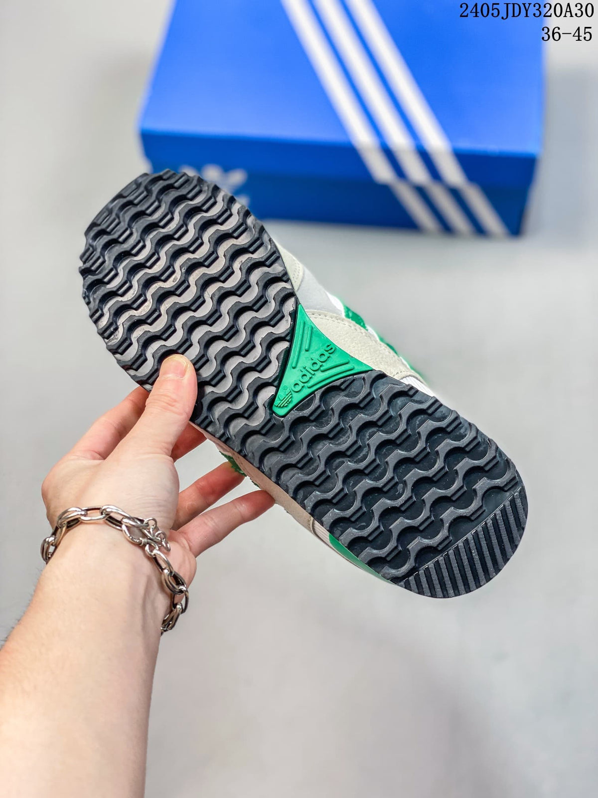 Close-up of the patterned dark outsole on a white and green Adidas ZX 750 sneaker