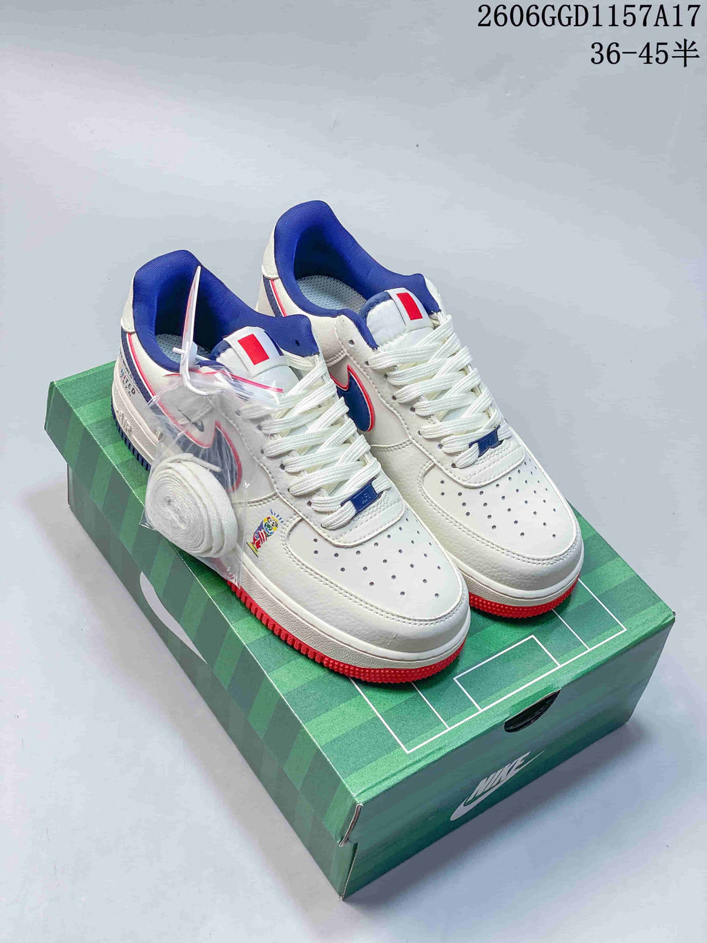 White low-top sneakers with blue and red accents shown on a green soccer-themed box