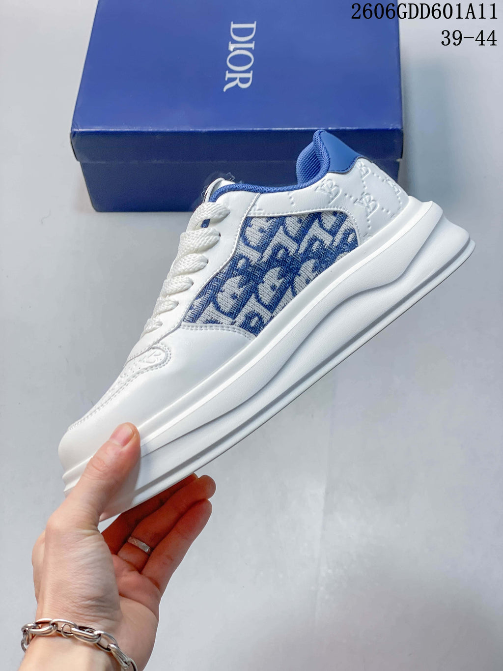 Side profile of a white low-top sneaker with blue patterned panels, blue collar accents, and a thick sole; image marking shows sizes 39–44.