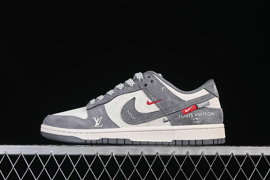 Side view of a grey and white low-top sneaker with red accents and decorative monogram motifs