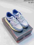 Pair of Nike Air Max 1 '86 Premium sneakers in gray-lavender, blue, and cream, shown on a shoe box.