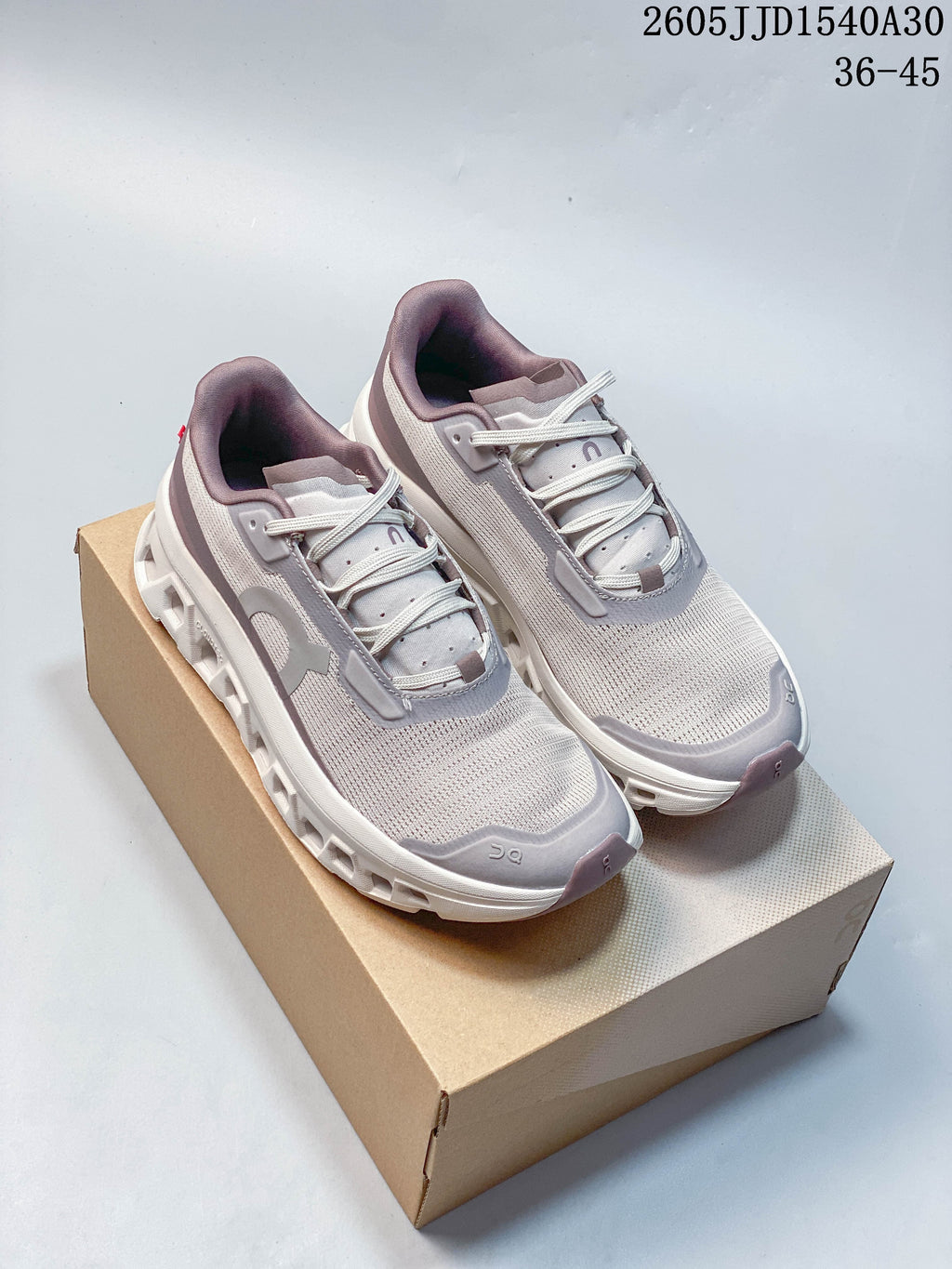 Pair of pale gray and white On Cloudmonster 2 running shoes with muted mauve and gray accents.