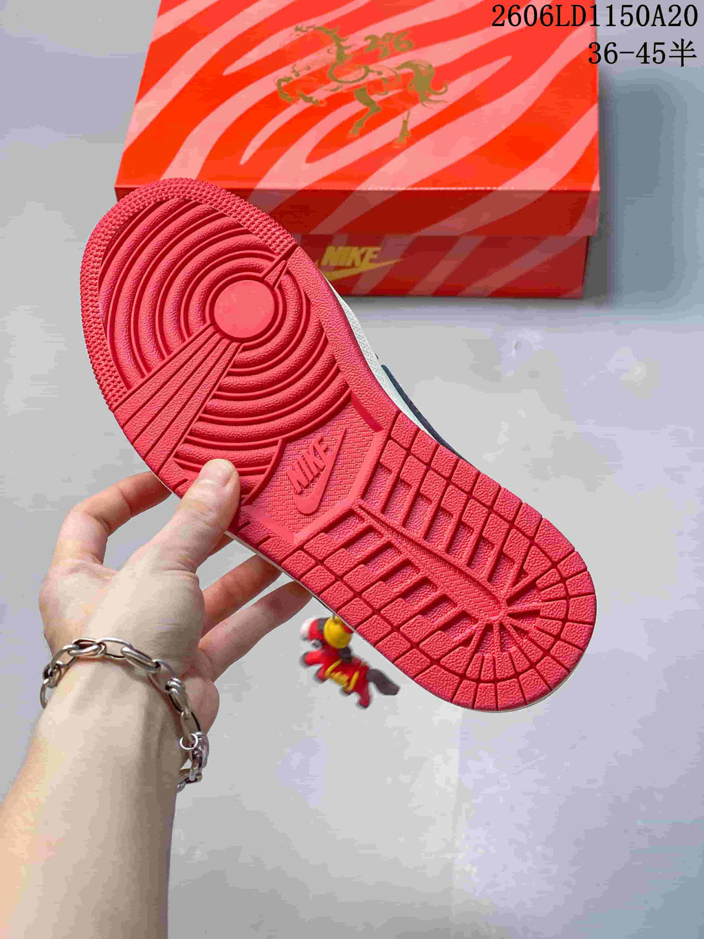 Red outsole of a low-top sneaker beside a patterned box