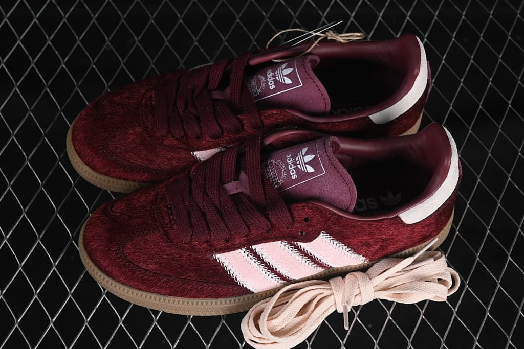 Pair of burgundy and pale pink sneakers with an extra pair of pale laces