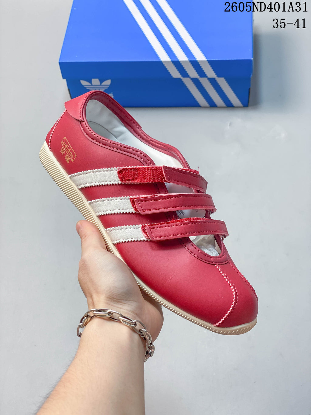 Angled side view of the red sneaker with white stripes and cream outsole