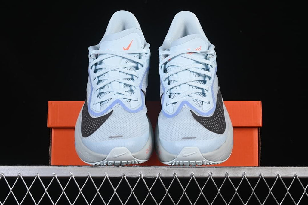 Front view of the pair of light blue running shoes on an orange shoe box.