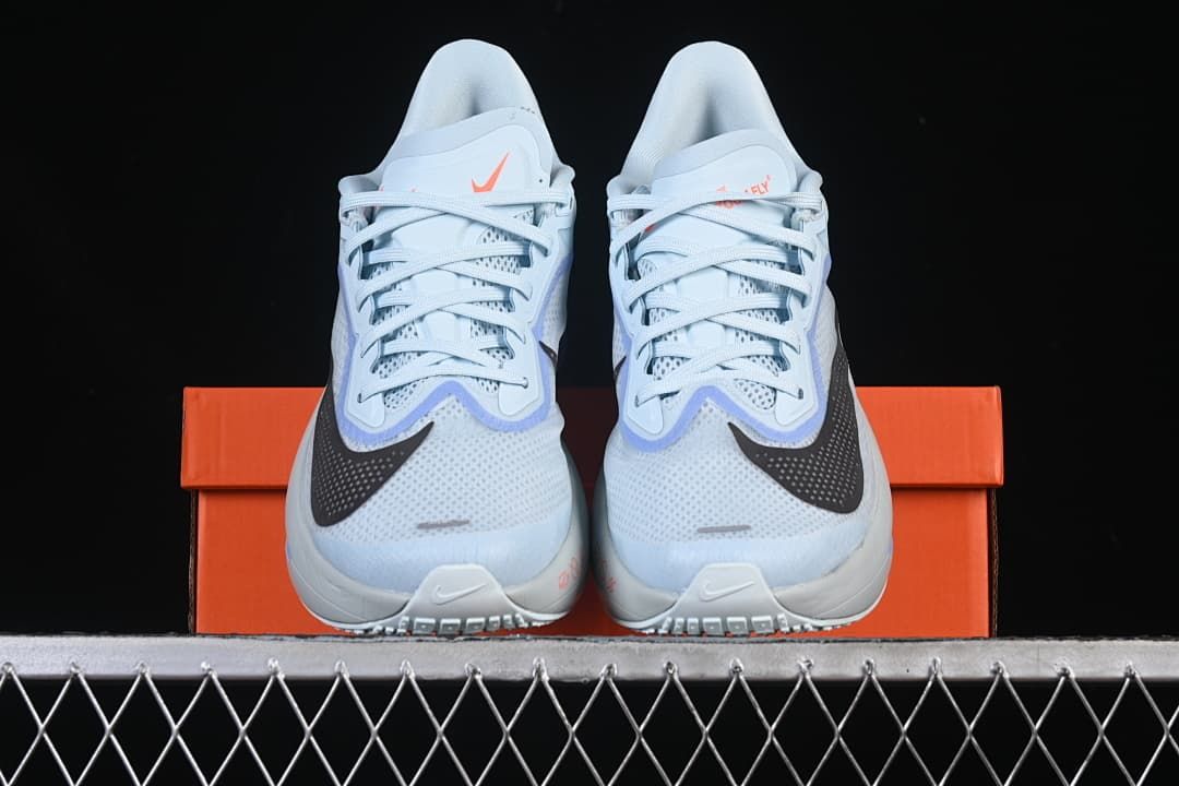 Front view of the pair of light blue running shoes on an orange shoe box.