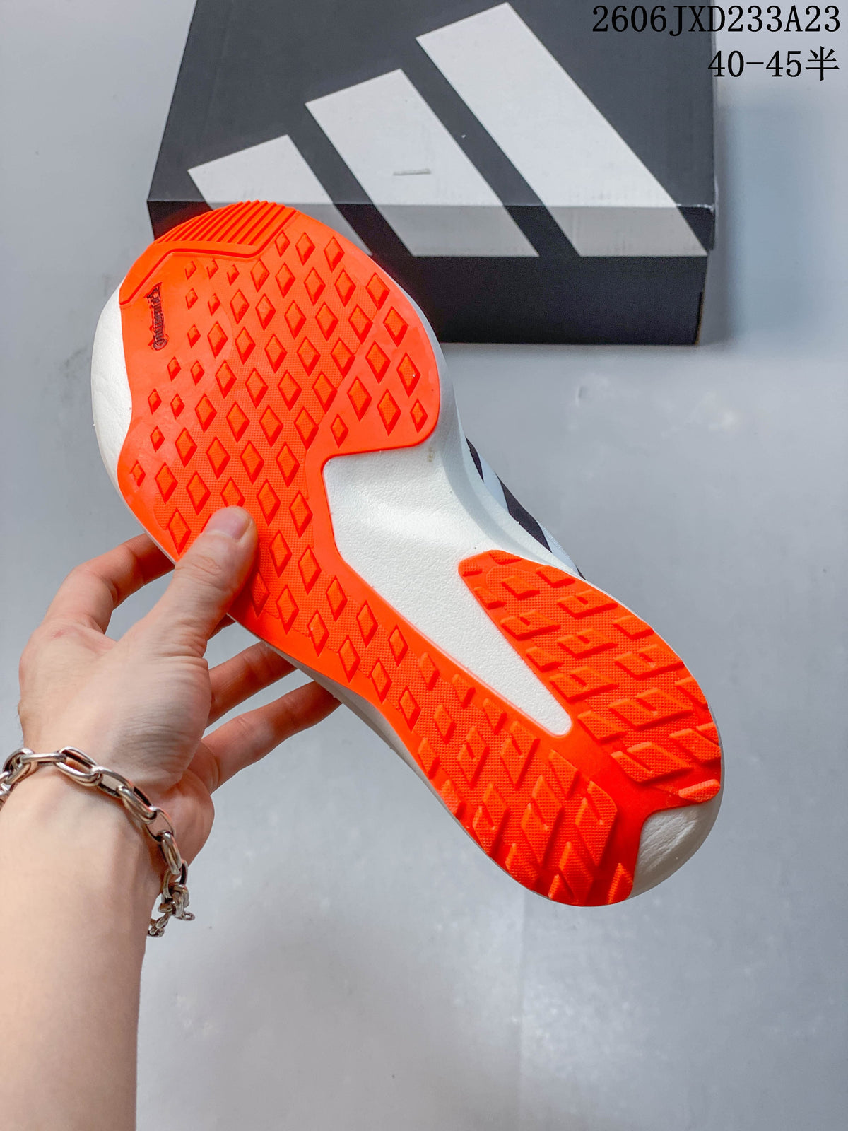 Close-up of the orange patterned outsole on a white running shoe