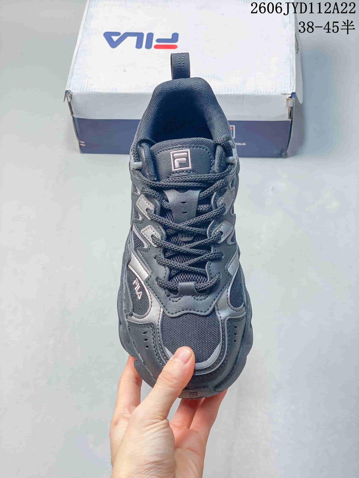 Front view of a gray FILA sneaker with mesh sections and lace-up closure