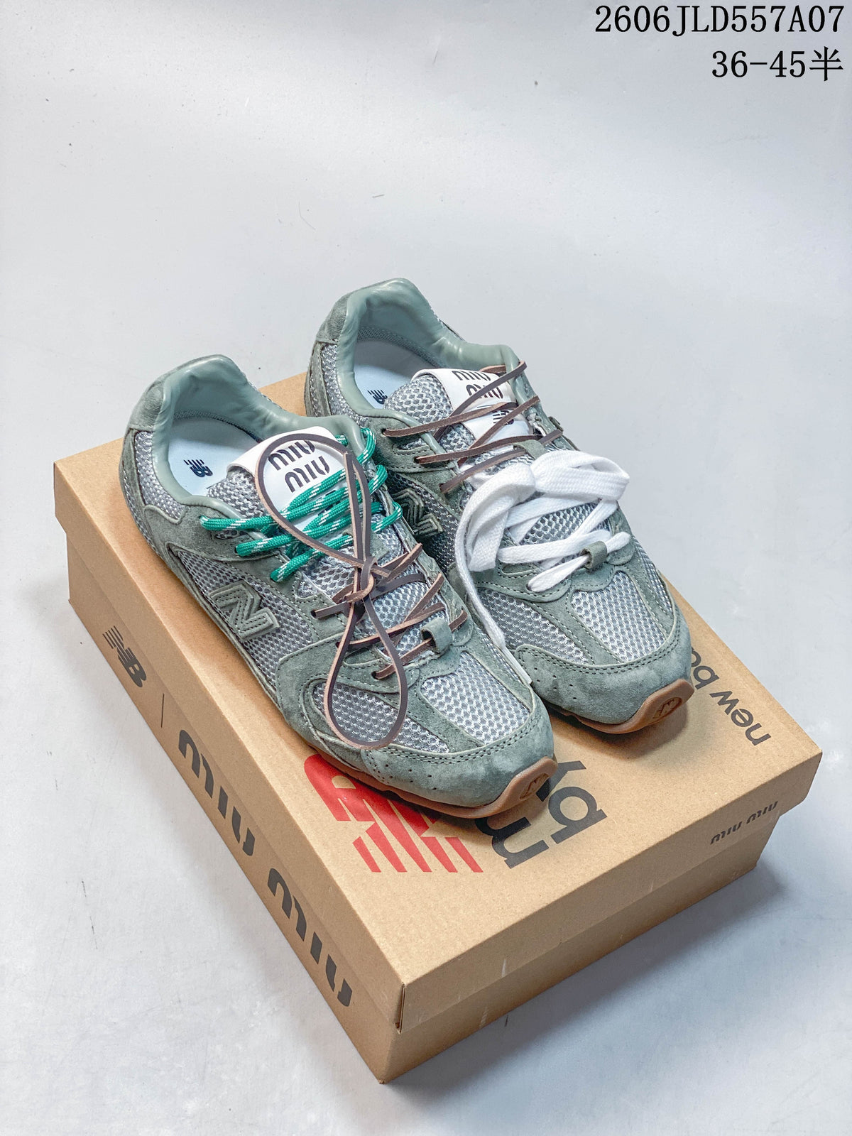 Pair of sage-green and silver Miu Miu x New Balance 530 SL sneakers with contrasting laces, shown on a branded shoe box