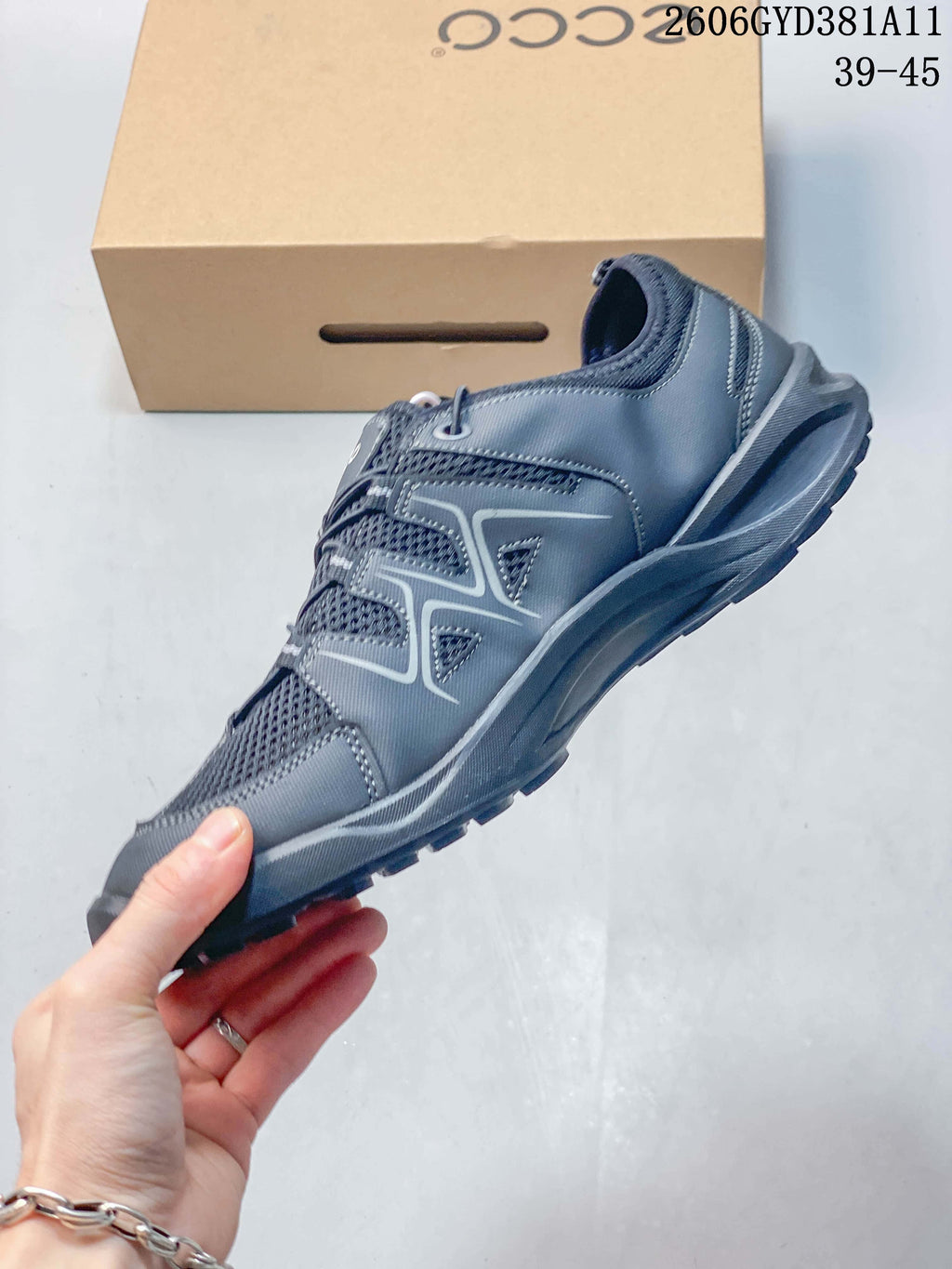 Side profile of a gray sneaker with mesh-look panels and contrasting overlays.