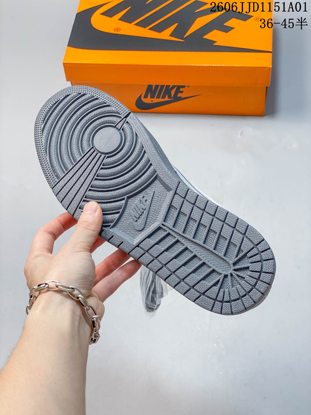 Gray outsole of the low-top sneaker shown beside an orange Nike shoe box