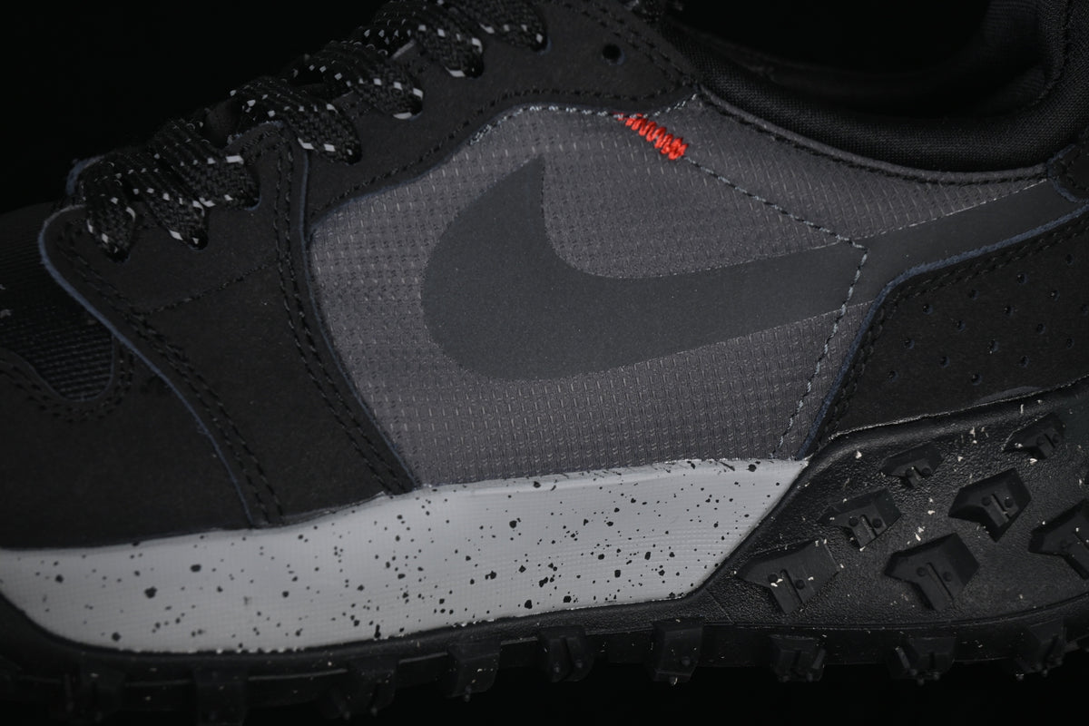 Close-up of the dark gray side panel, black Swoosh, orange stitching, and speckled midsole