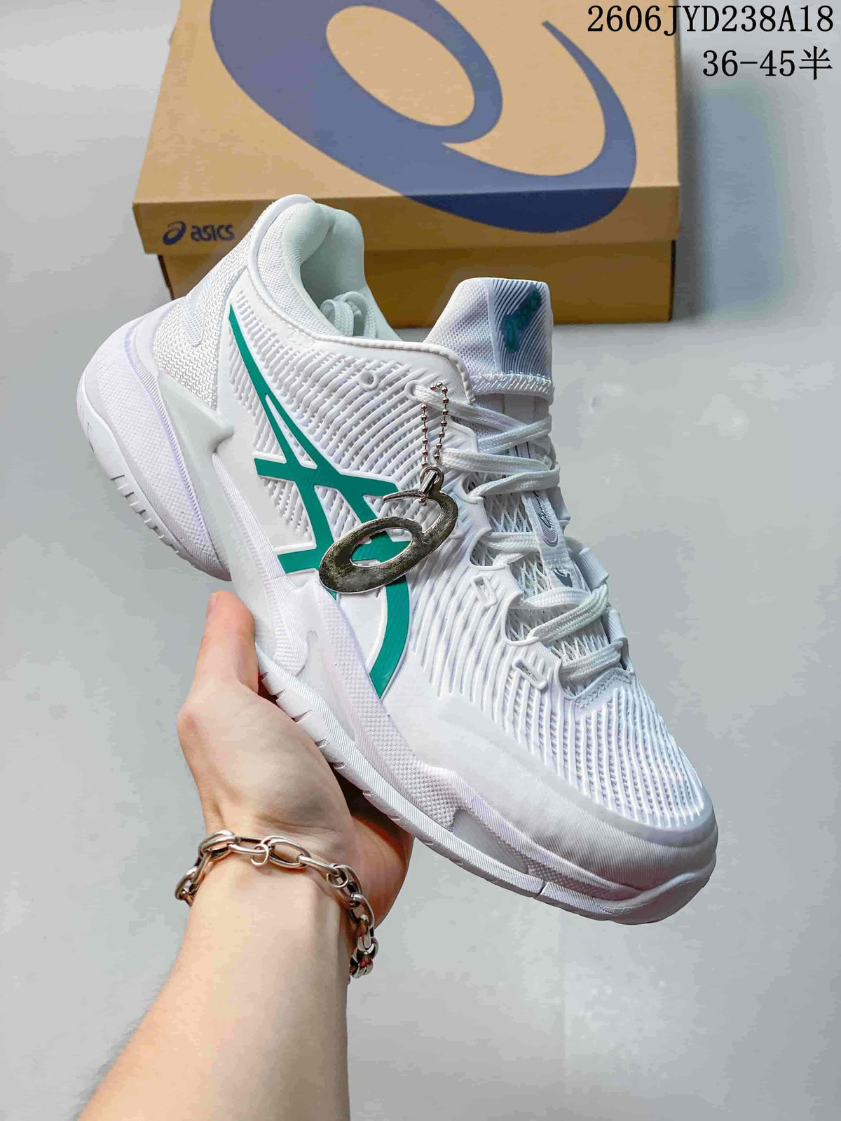 Angled side view of the white tennis shoe with green accents