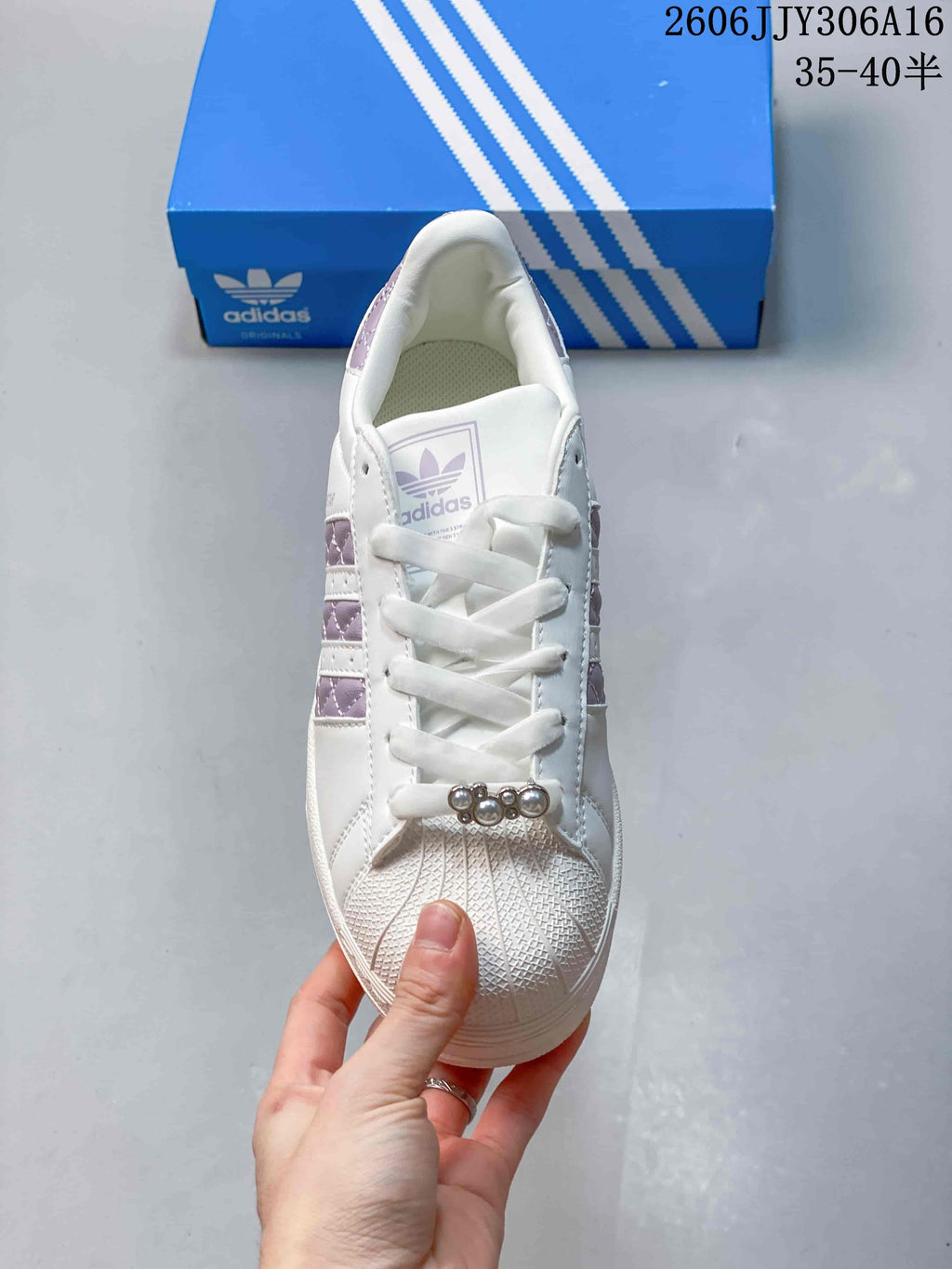 Top view of the sneaker with white laces, shell toe, and lace charm