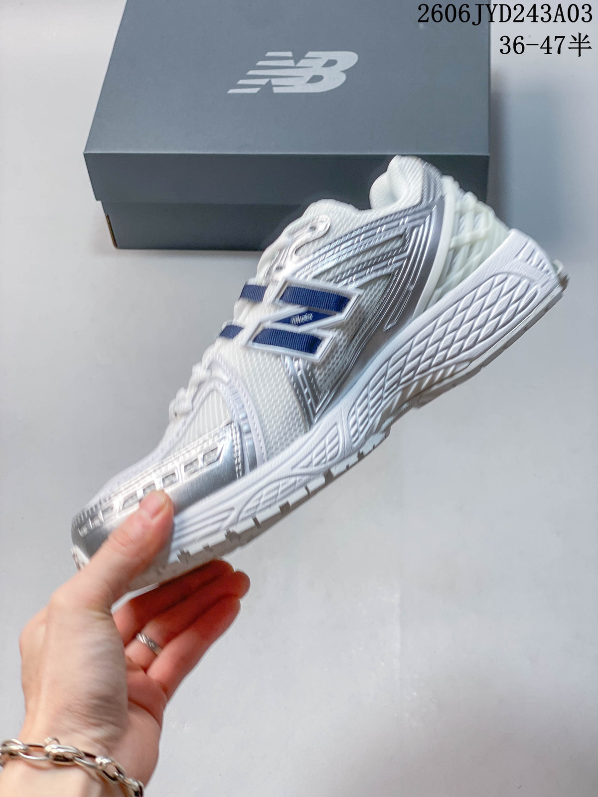 Side view of a white and silver New Balance sneaker with navy accents