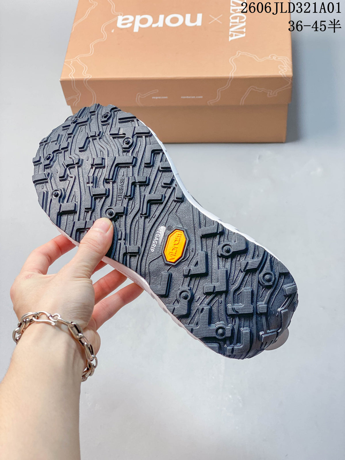 Underside of a shoe showing a dark lugged outsole and a small contrasting badge.