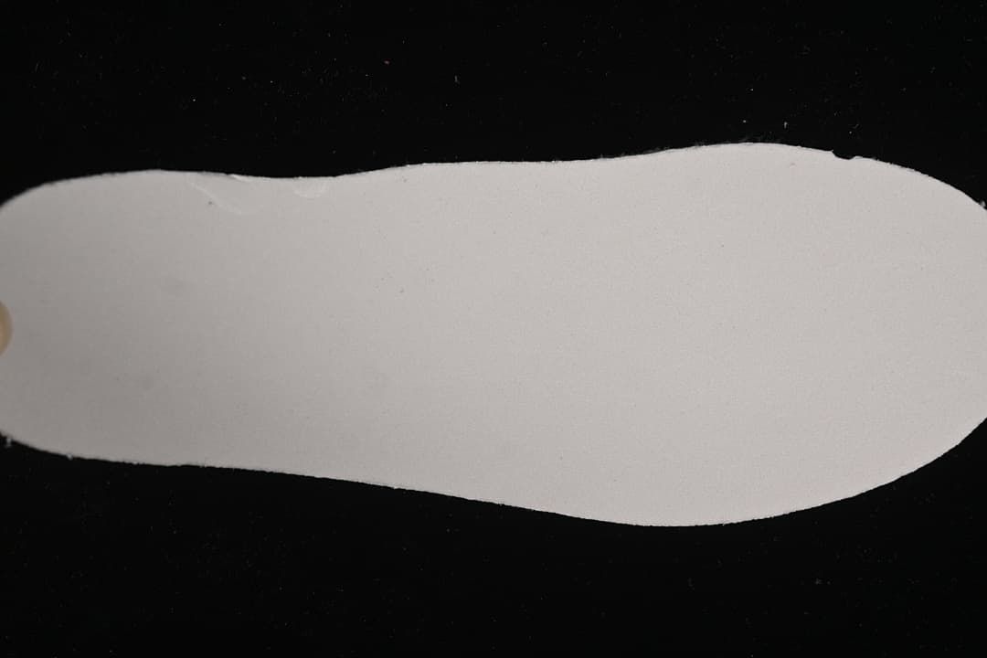 Plain light-colored shoe insole shown against a dark background