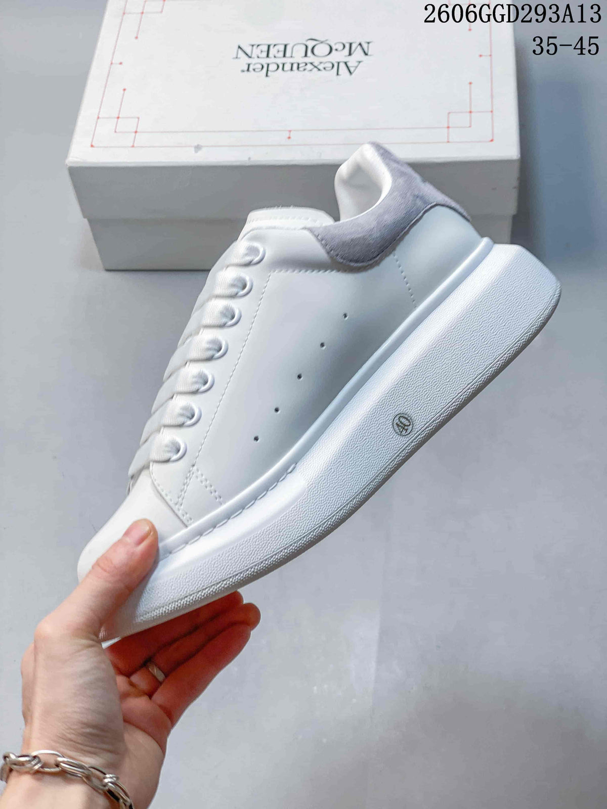 Side view of a white low-top sneaker with a gray heel panel and perforated details
