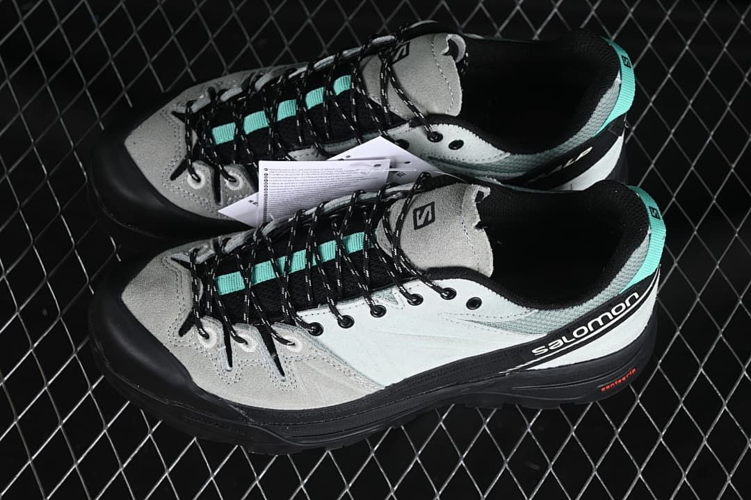 Pair of grey, black, and turquoise Salomon X-ALP shoes.