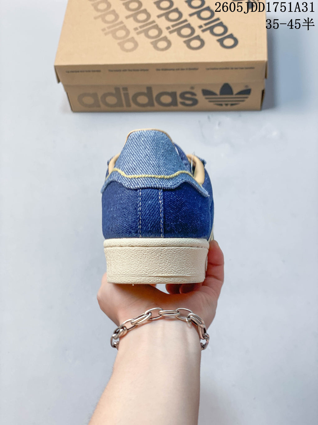 Rear view of a blue denim-look sneaker with a cream heel and sole
