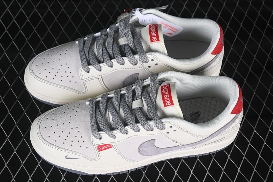 Pair of off-white and grey low-top sneakers with grey laces, perforated toe panels, red heel accents and visible branding.