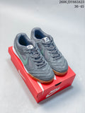 Pair of gray Nike Gato low-top sneakers with sage-green Swooshes and gum outsoles on a red shoebox