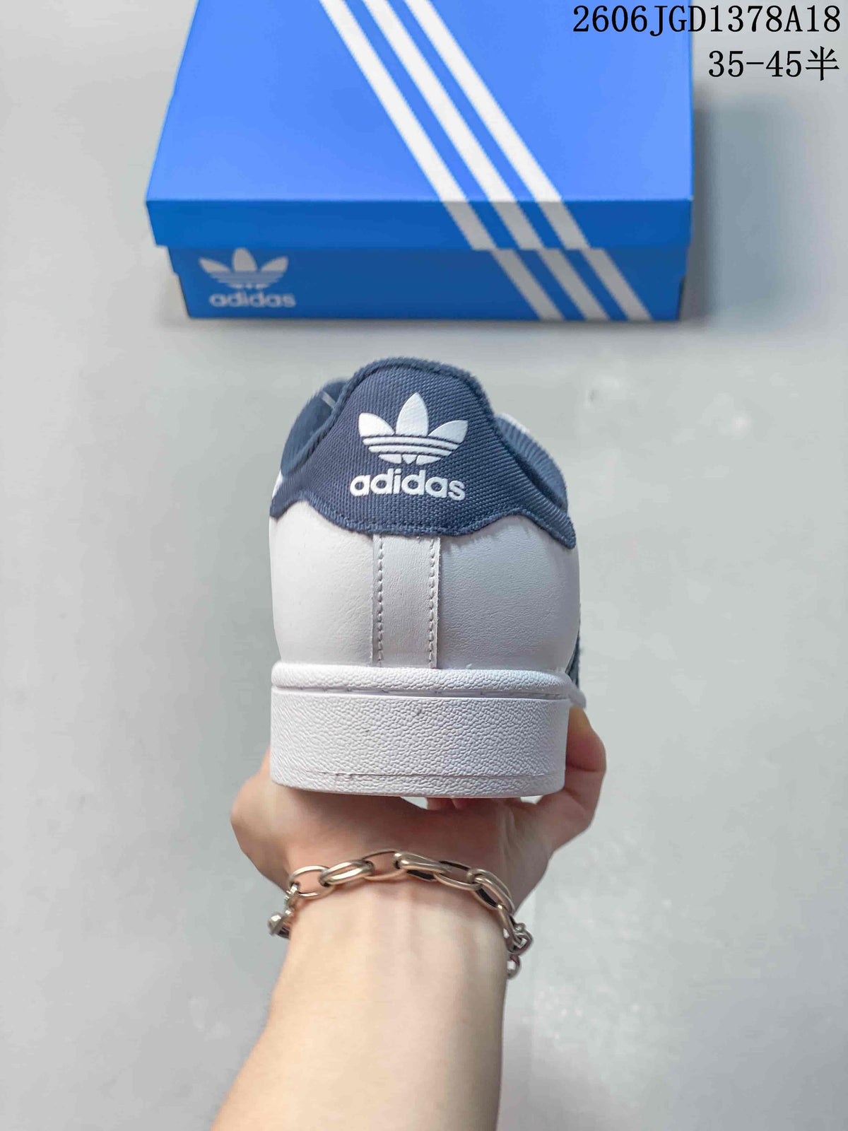 Rear view of a white Adidas sneaker with a navy heel tab and trefoil logo.