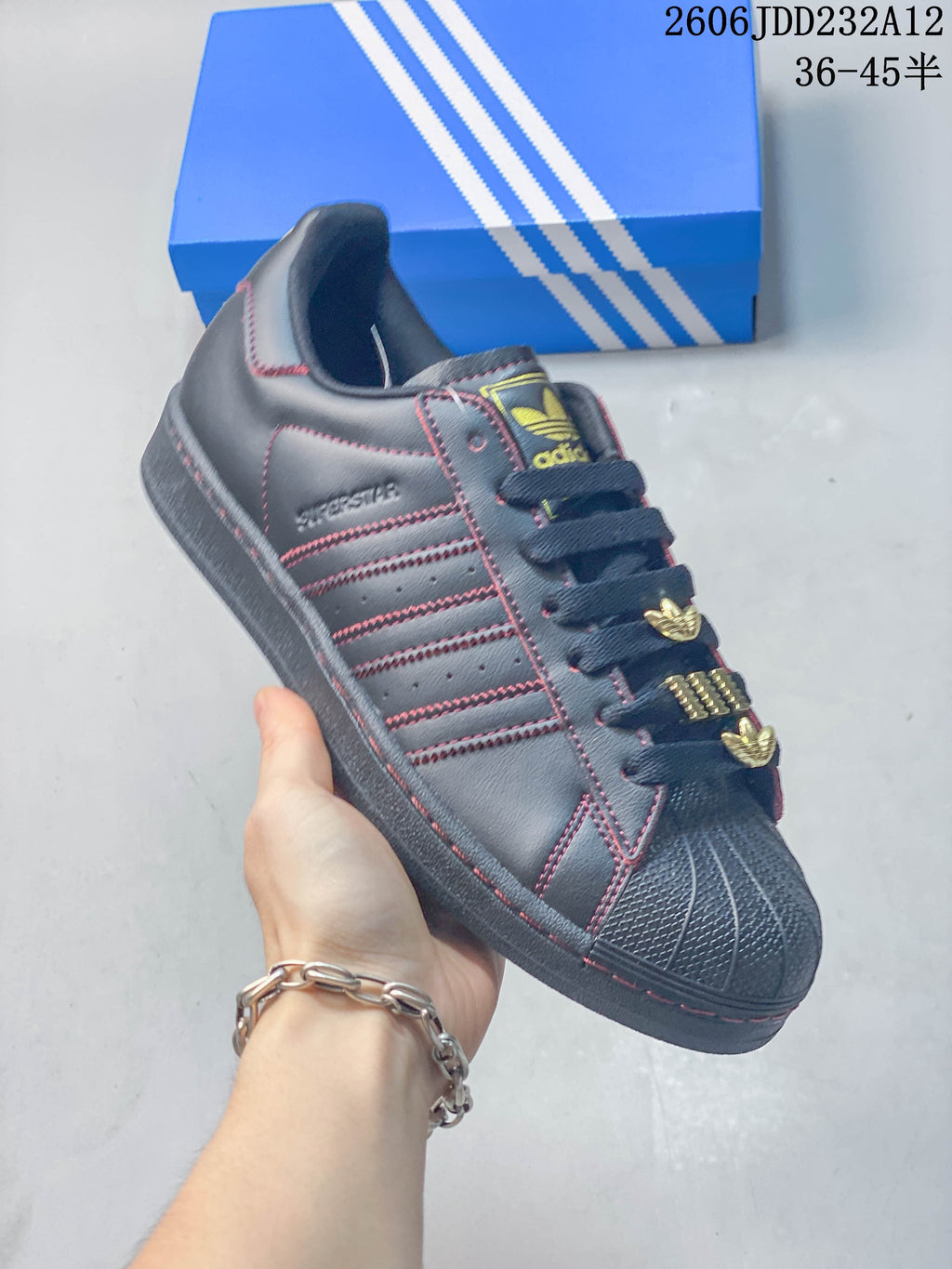 Angled close-up showing the side stripes, red stitching, shell toe, and gold-tone lace accents.