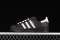 Side view of a black adidas Superstar sneaker with pink stripes, laces, and heel tab